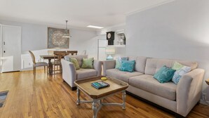 A living room with a beige sofa, a wooden coffee table, and a dining area with a table and chairs.