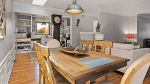 A dining area with a wooden table and chairs, a chandelier, and a view into the kitchen.