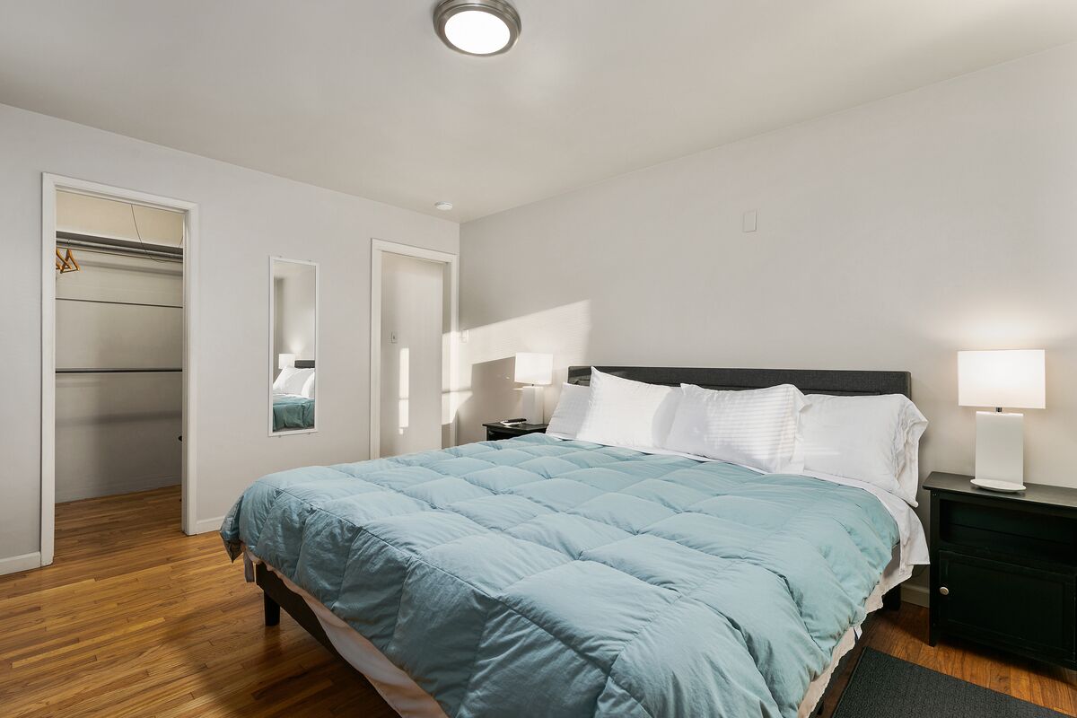 A bedroom with a bed, bedside tables, a wardrobe, and a mirror.