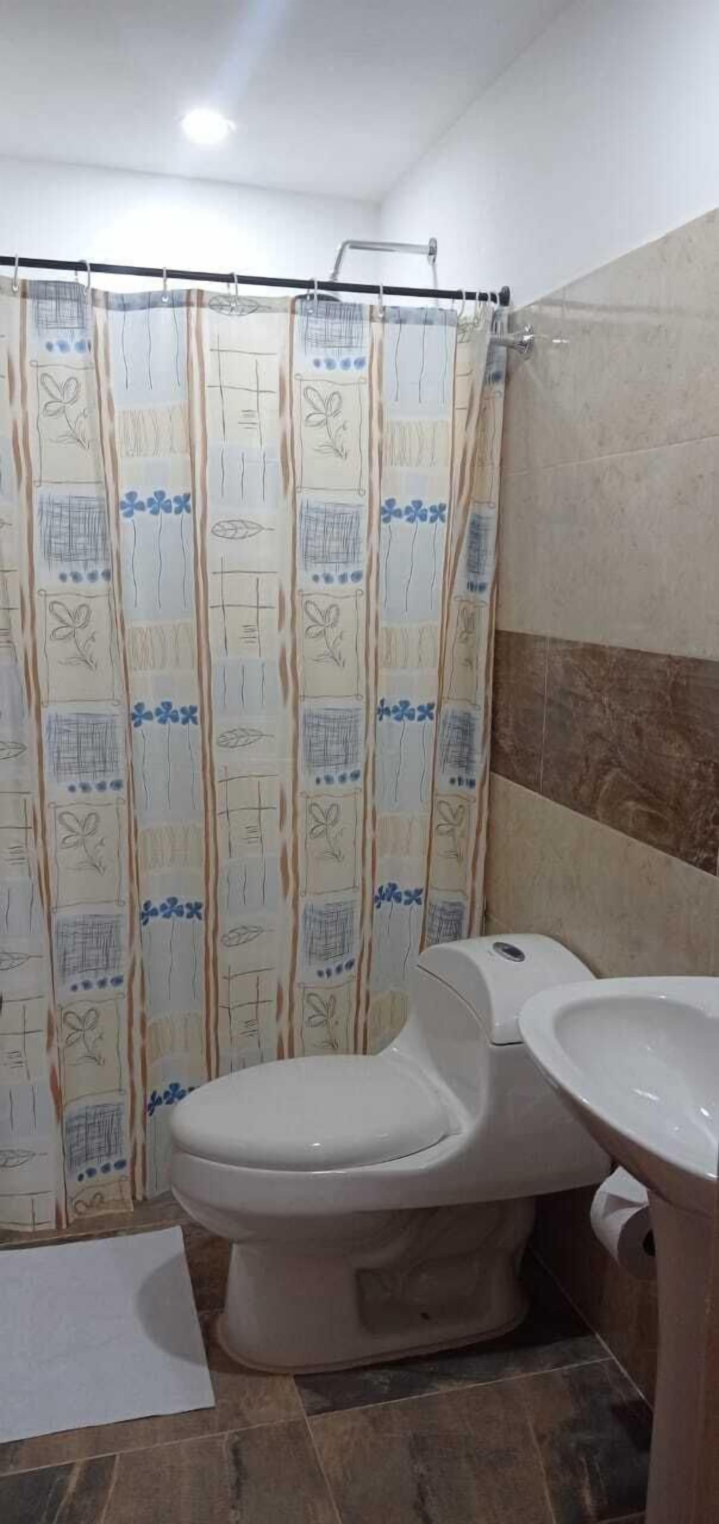 Un baño con inodoro, lavamanos y cortina de ducha.