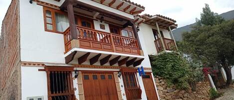 Un edificio de dos plantas con balcones de madera y un muro de piedra.