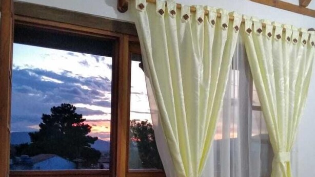 A room with a bed, a window with curtains, a view of the sky, and a balcony with a railing. - CASA HOTEL LA VILLA DEL ROSARIO (Villa de Leyva)