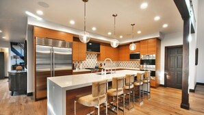 Una cocina moderna con una isla grande, electrodomésticos de acero inoxidable, armarios de madera y taburetes de bar.