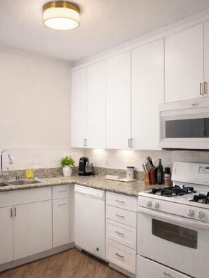 A modern kitchen with white cabinets, a built-in microwave, a gas stove, and a dishwasher.