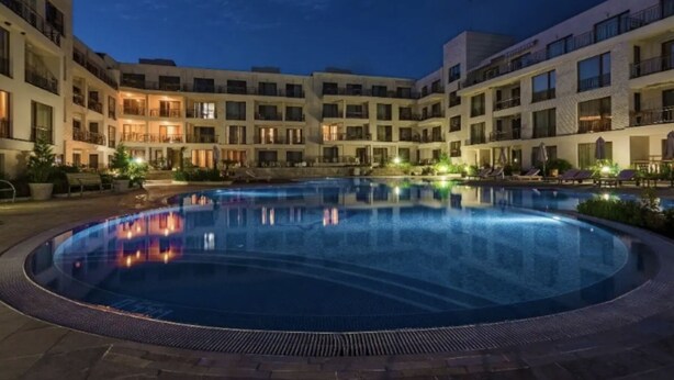 A hotel courtyard with a swimming pool, multiple balconies, and well-lit buildings. - Serene King Bed Condo, Marina Del Rey (Marina del Rey)