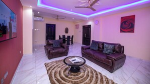 A modern living room with two leather sofas, a glass coffee table, and a ceiling fan.