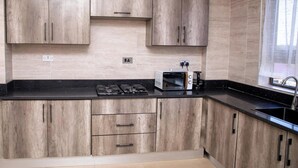 A modern kitchen with wooden cabinets, a black countertop, a built-in stove, and a microwave.