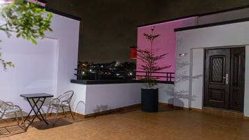 Un balcon avec une table et des chaises, un pot de fleurs et une vue sur la ville la nuit.