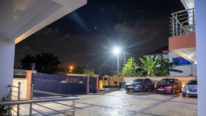 A parking area with cars, a metal railing, and a building in the background.