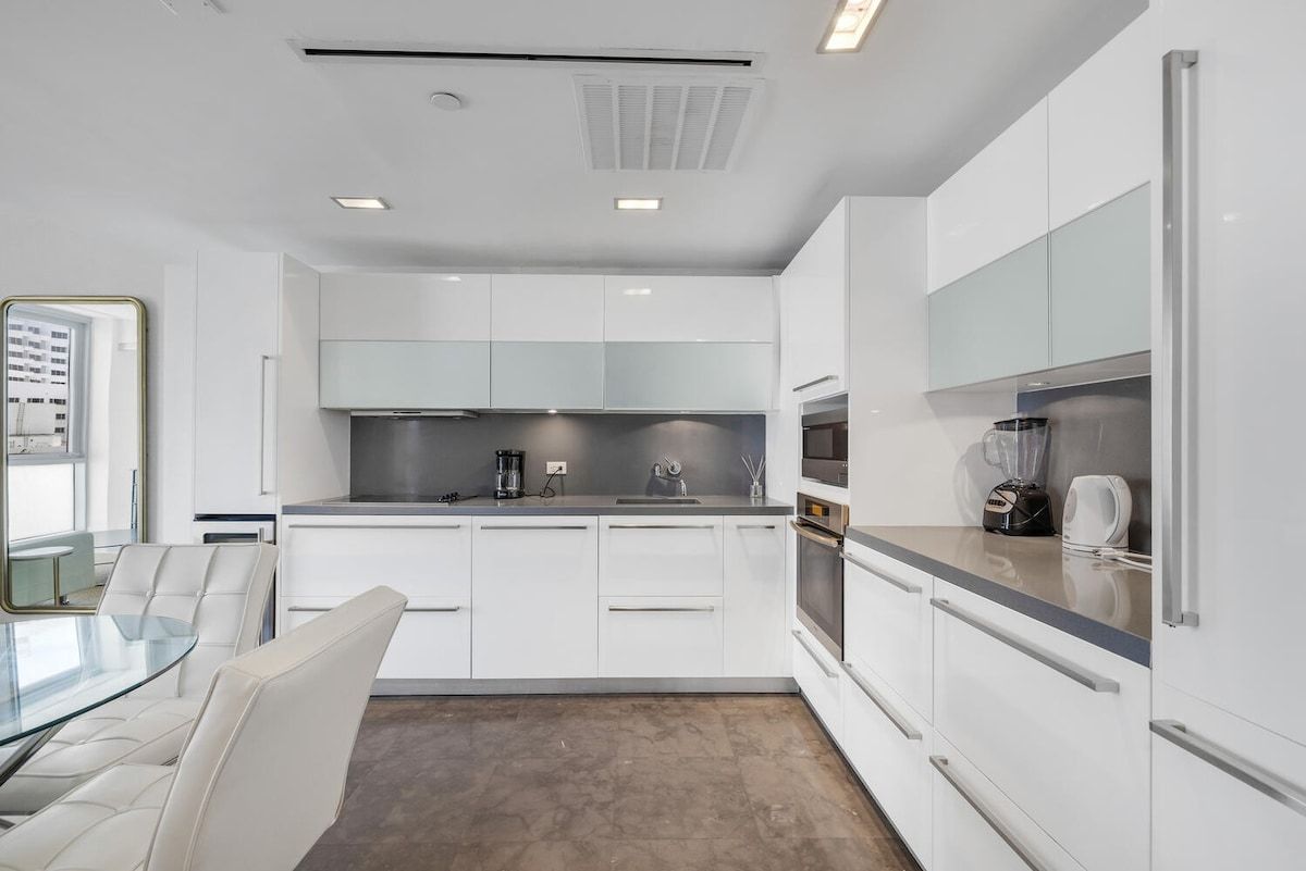 Une cuisine moderne avec des meubles blancs, un îlot central et des appareils électroménagers intégrés.