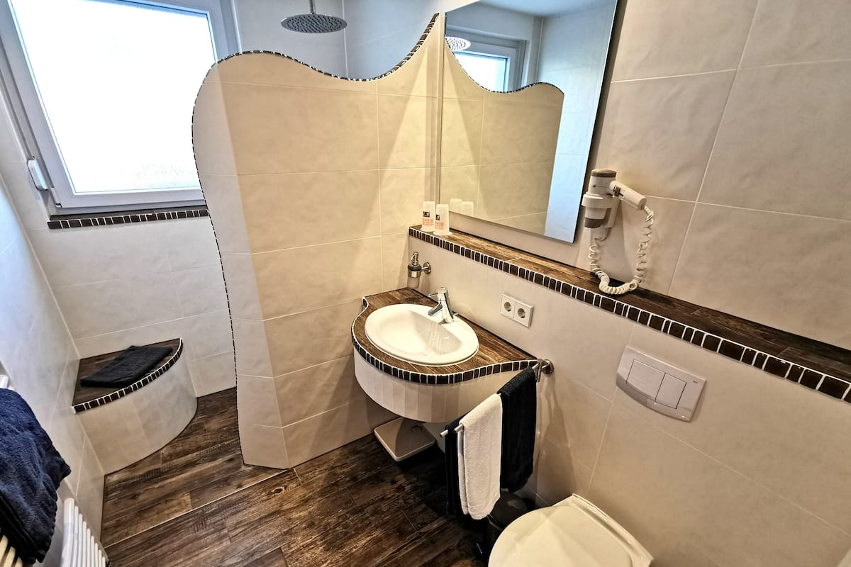 Un baño con suelo de madera, un lavabo, un inodoro y una ducha.