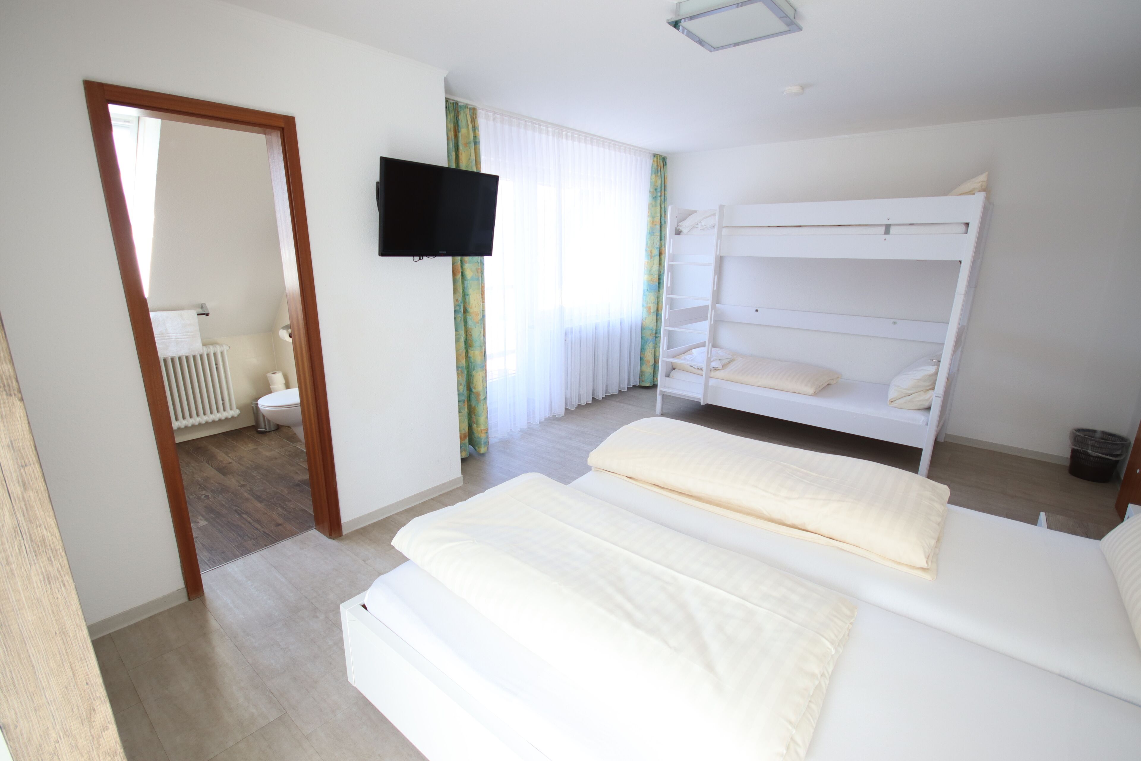 Ein Schlafzimmer mit zwei Betten, einem Fernseher und Blick auf das Badezimmer.