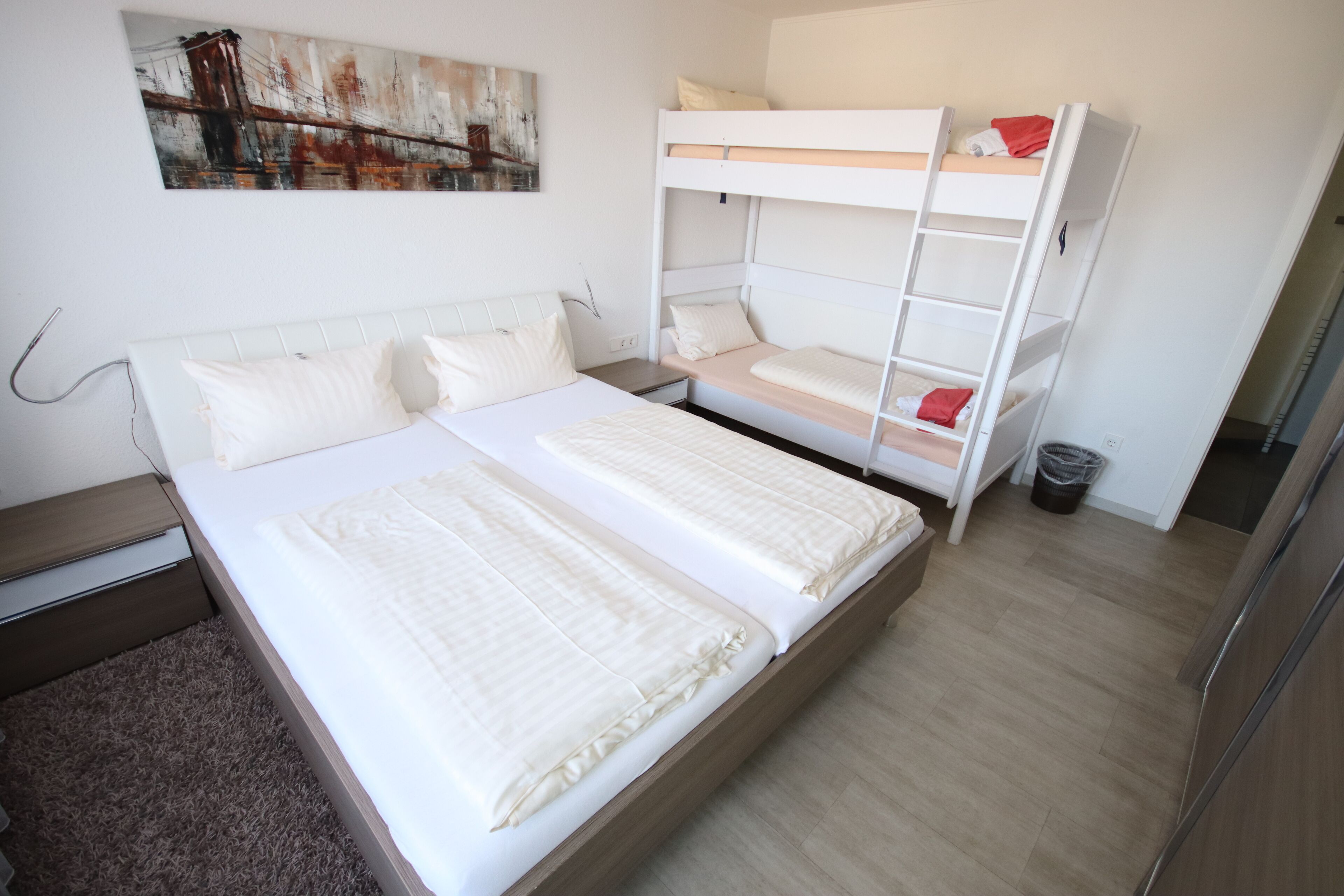 Ein Schlafzimmer mit einem Etagenbett, einem Einzelbett und einem Nachttisch.