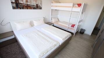Ein Schlafzimmer mit einem Etagenbett, einem Einzelbett und einem Nachttisch.
