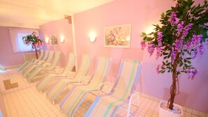 A row of striped lounge chairs in a spa area with a potted tree and wall-mounted lights. - Appartements Biedermeier (Bad Krozingen)