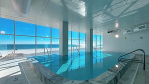 Piscina interna com vista para a praia e oceano.