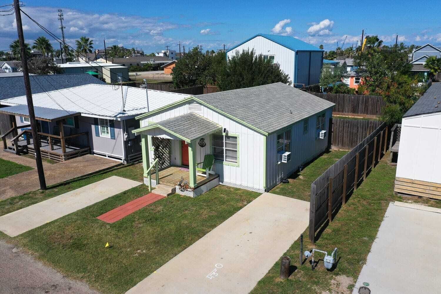 A single-story house with a front porch, a small deck, and a fenced backyard.