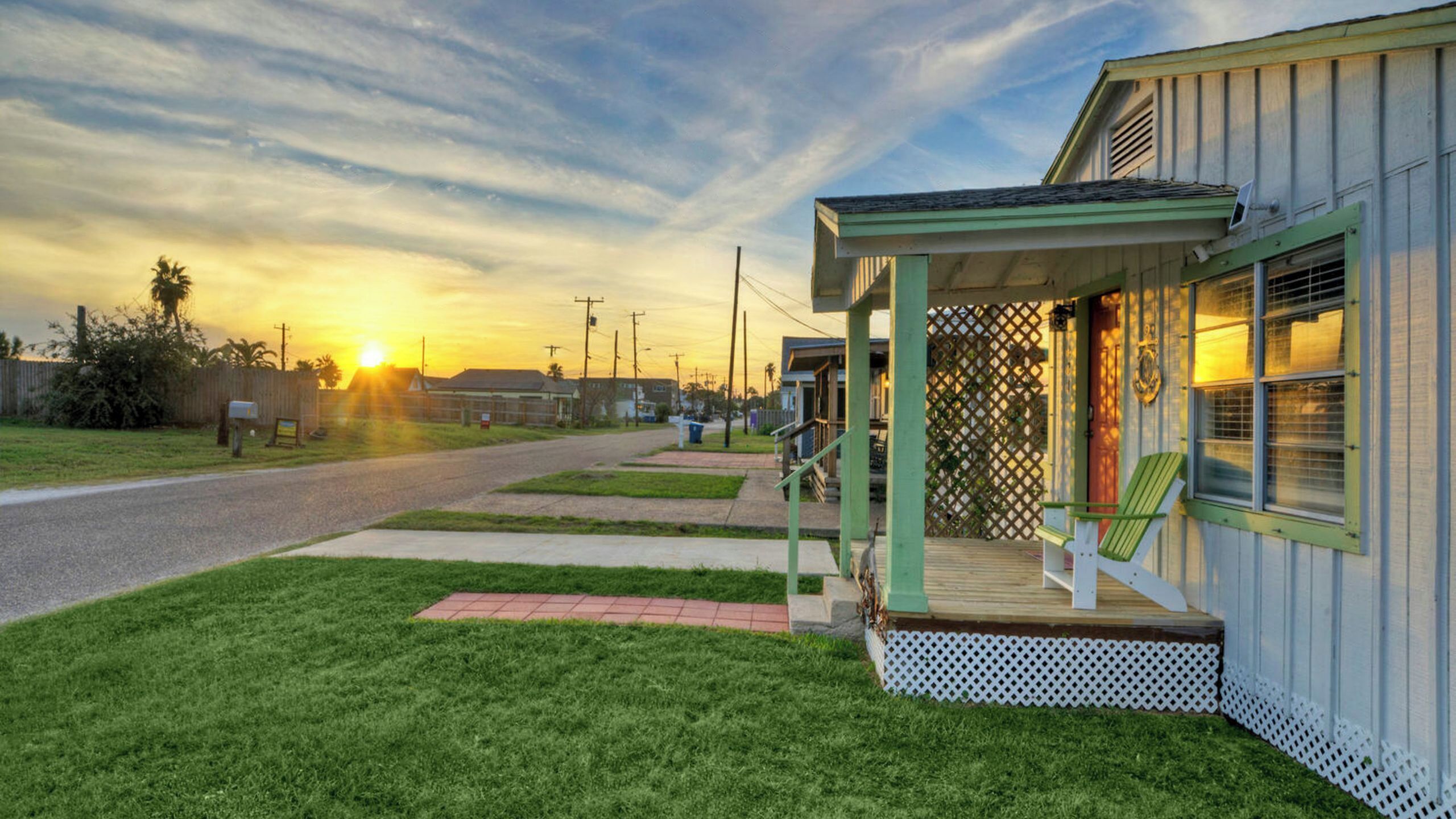 A single-story building with a porch, a small deck, and a view of the sunset.