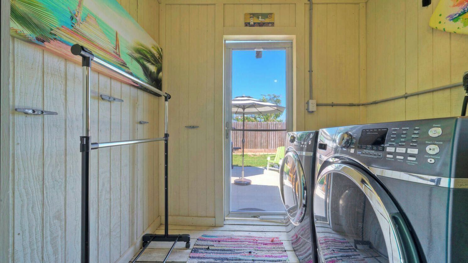 A laundry room with a washing machine, a drying rack, and a door leading outside.