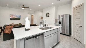 A modern kitchen with a central island, stainless steel appliances, and a dining area with a sofa and table. - Exquisite 3 bedroom house located in a very quiet area of Katy . (Katy)
