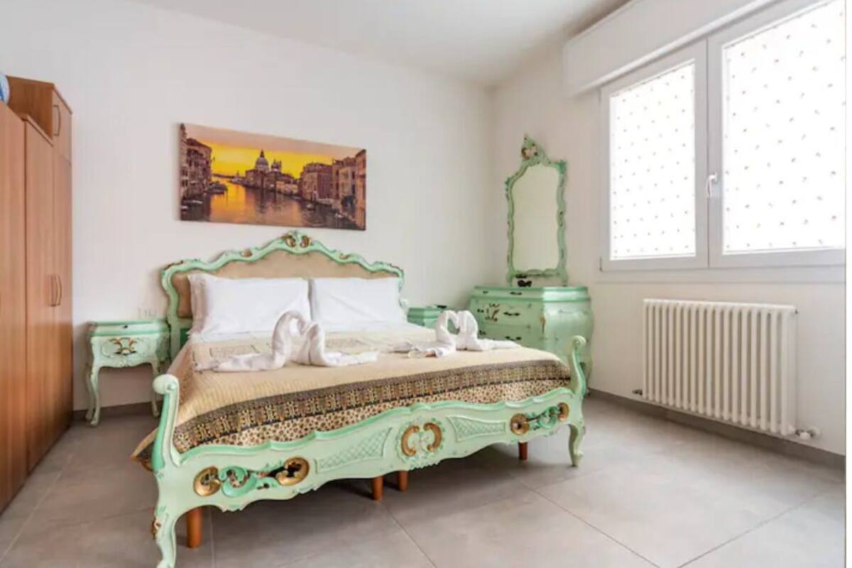 A bedroom with a bed, a dresser, a mirror, and a window.