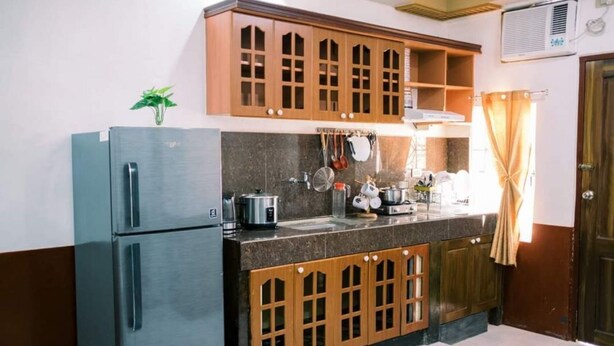 Eine Küche mit Holzschränken, einem Edelstahlkühlschrank und einem Spülbecken.