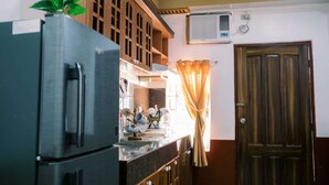 Eine Küche mit Kühlschrank, Schränken und einem Fenster mit Vorhängen.