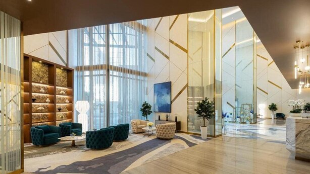 Um hall amplo com design moderno, incluindo uma área de estar com sofás e poltronas, uma janela grande que oferece luz natural e uma parede decorativa com prateleiras.
