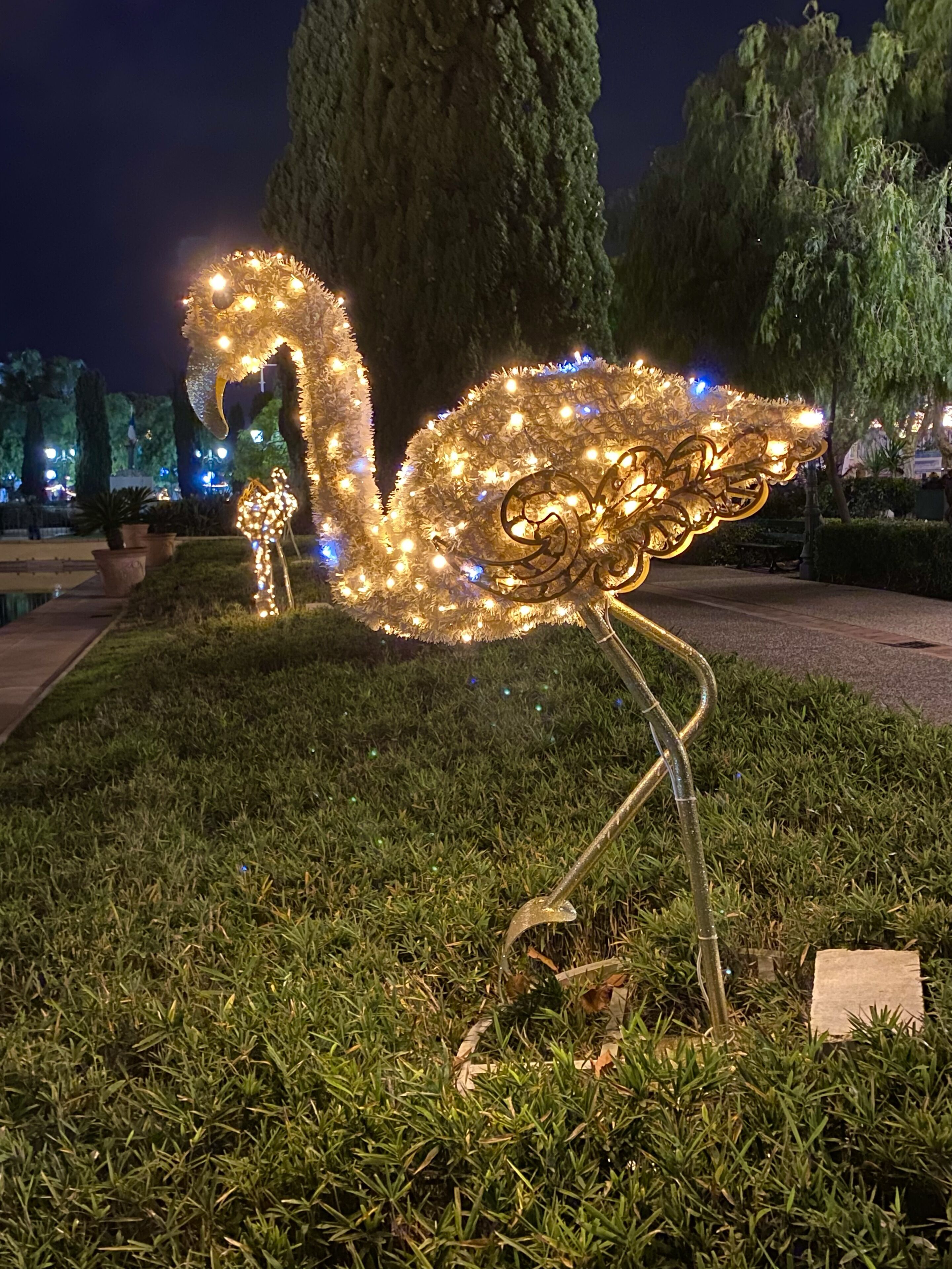 Una scultura luminosa decorativa a forma di cigno in un parco di notte.