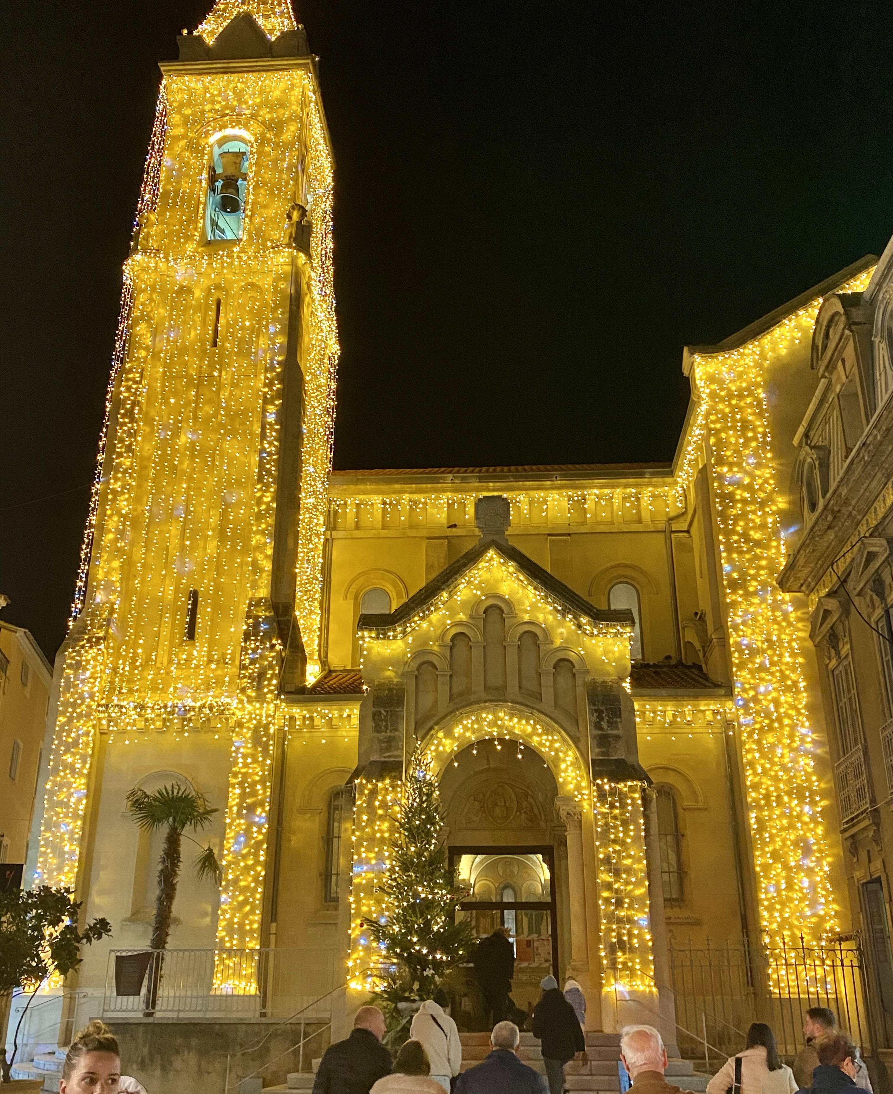 A historic building with a tall bell tower, decorated with string lights.
