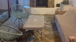 A cozy room with a stone fireplace, wicker furniture, and a stone floor. - House Sleeps 6-garden-freeparking-bbq-patio-petsok (Karnobat)