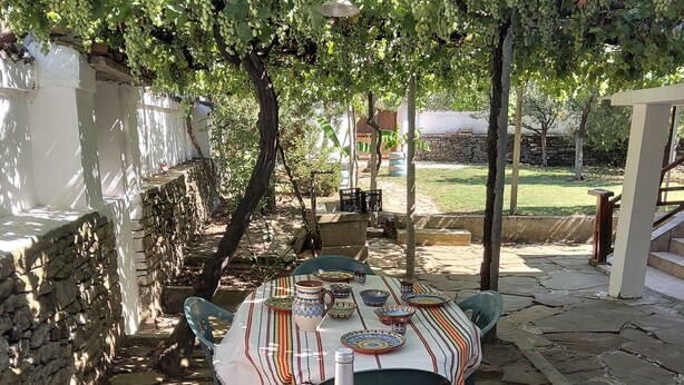 A table set outdoors with a bottle and glasses, surrounded by stone walls and greenery. - House Sleeps 6-garden-freeparking-bbq-patio-petsok (Karnobat)
