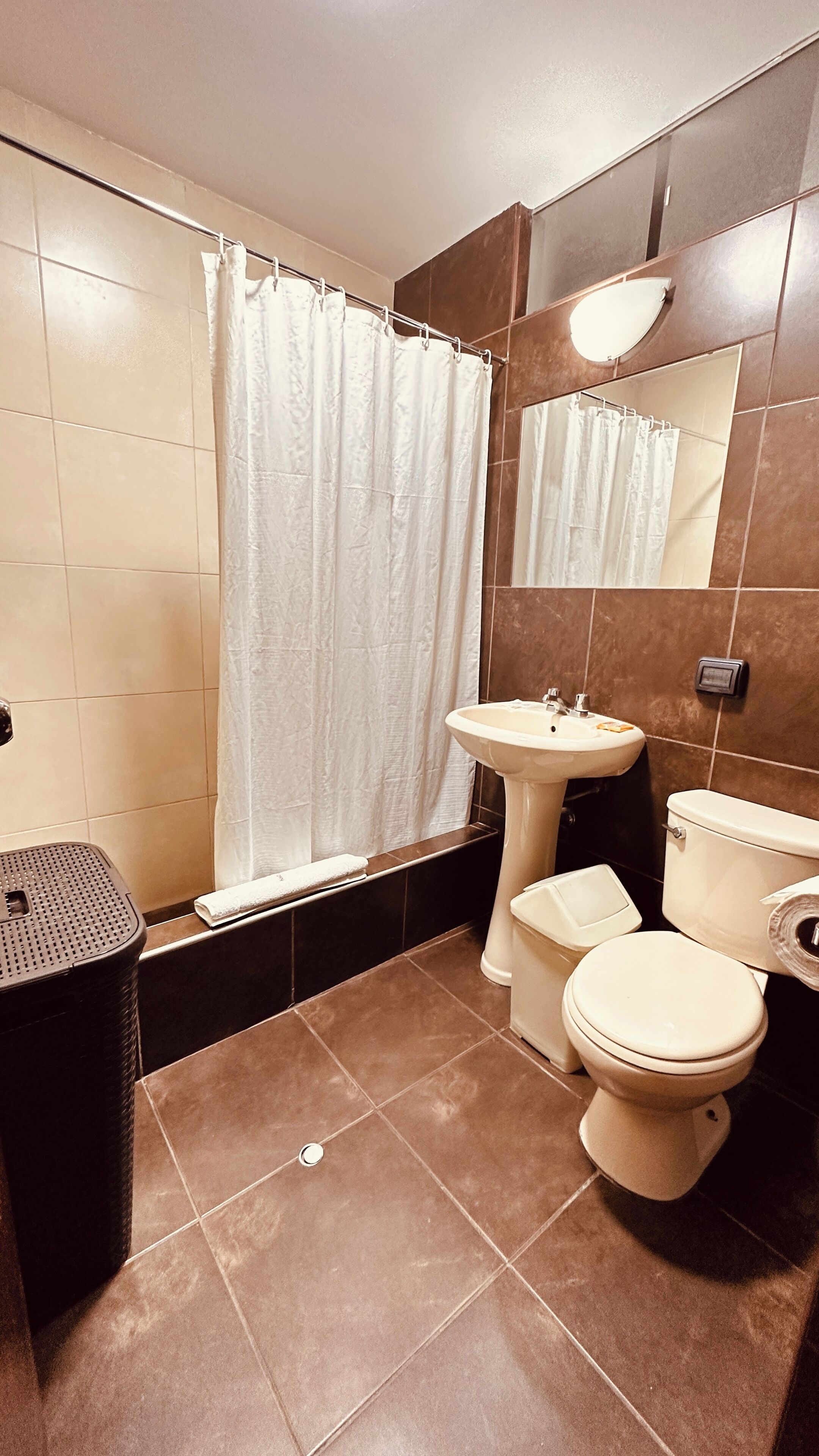 Un baño con bañera, lavamanos, inodoro y un cubo de basura.