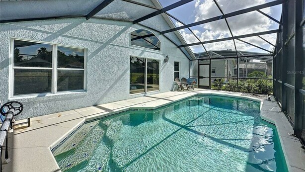 Une maison moderne dotée d’une piscine, de grandes fenêtres et d’un patio couvert.