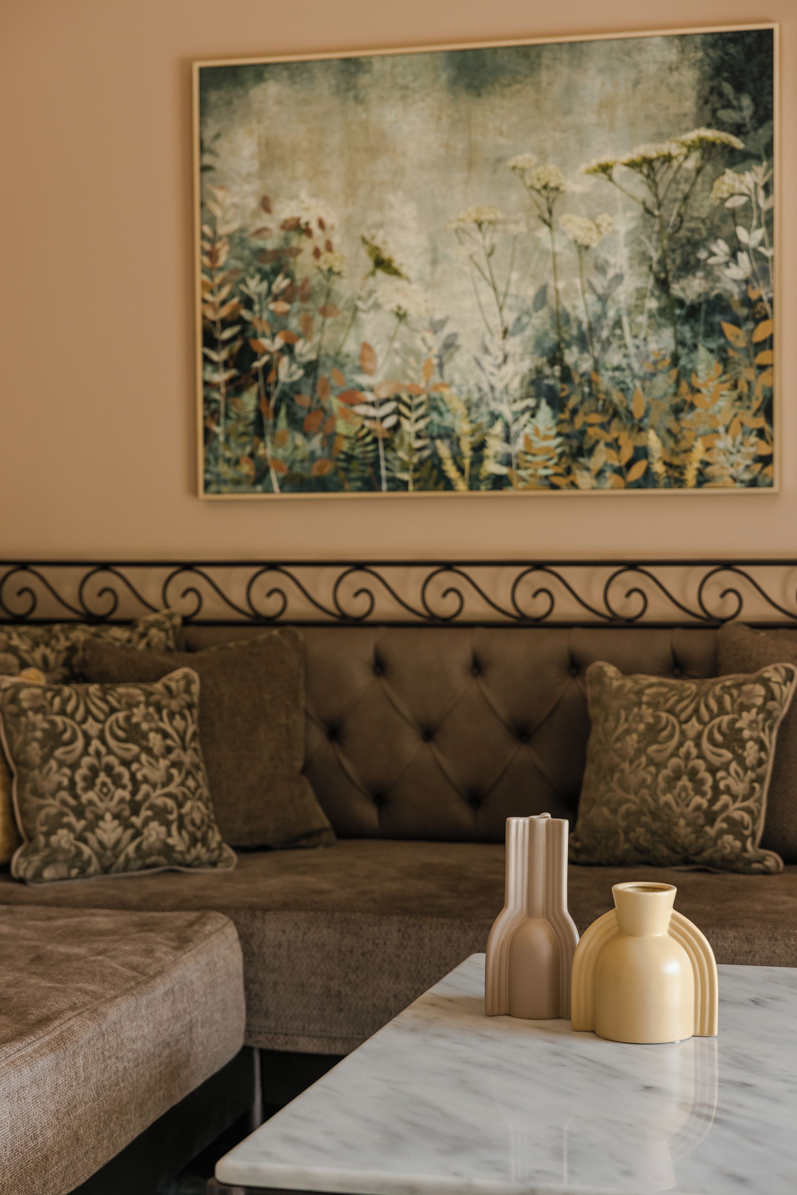 Ein Wohnzimmer mit einem braunen Sofa, gemusterten Kissen, einem Marmortisch und zwei Vasen.