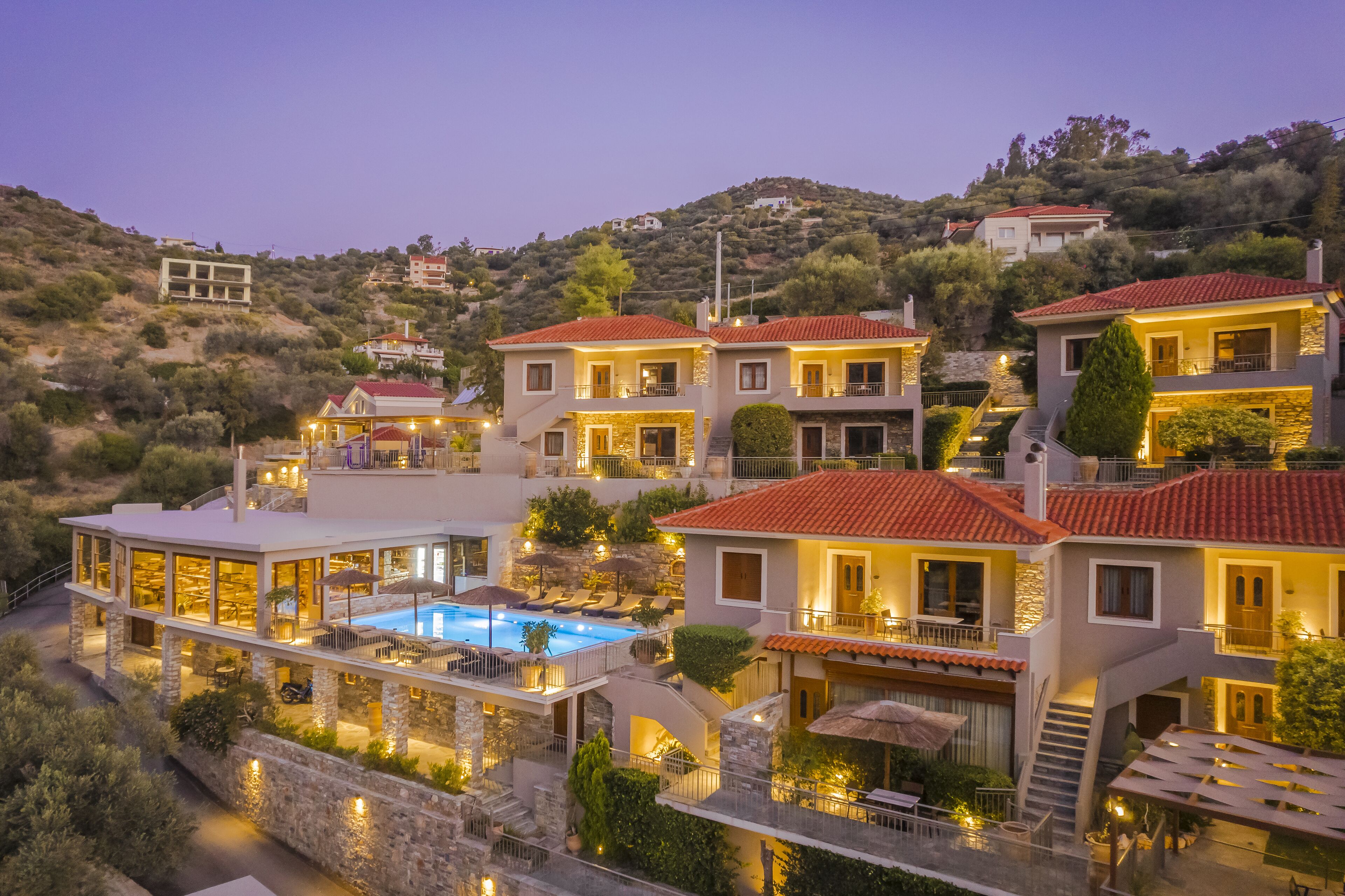 A hillside property with multiple buildings, a swimming pool, and outdoor seating areas.