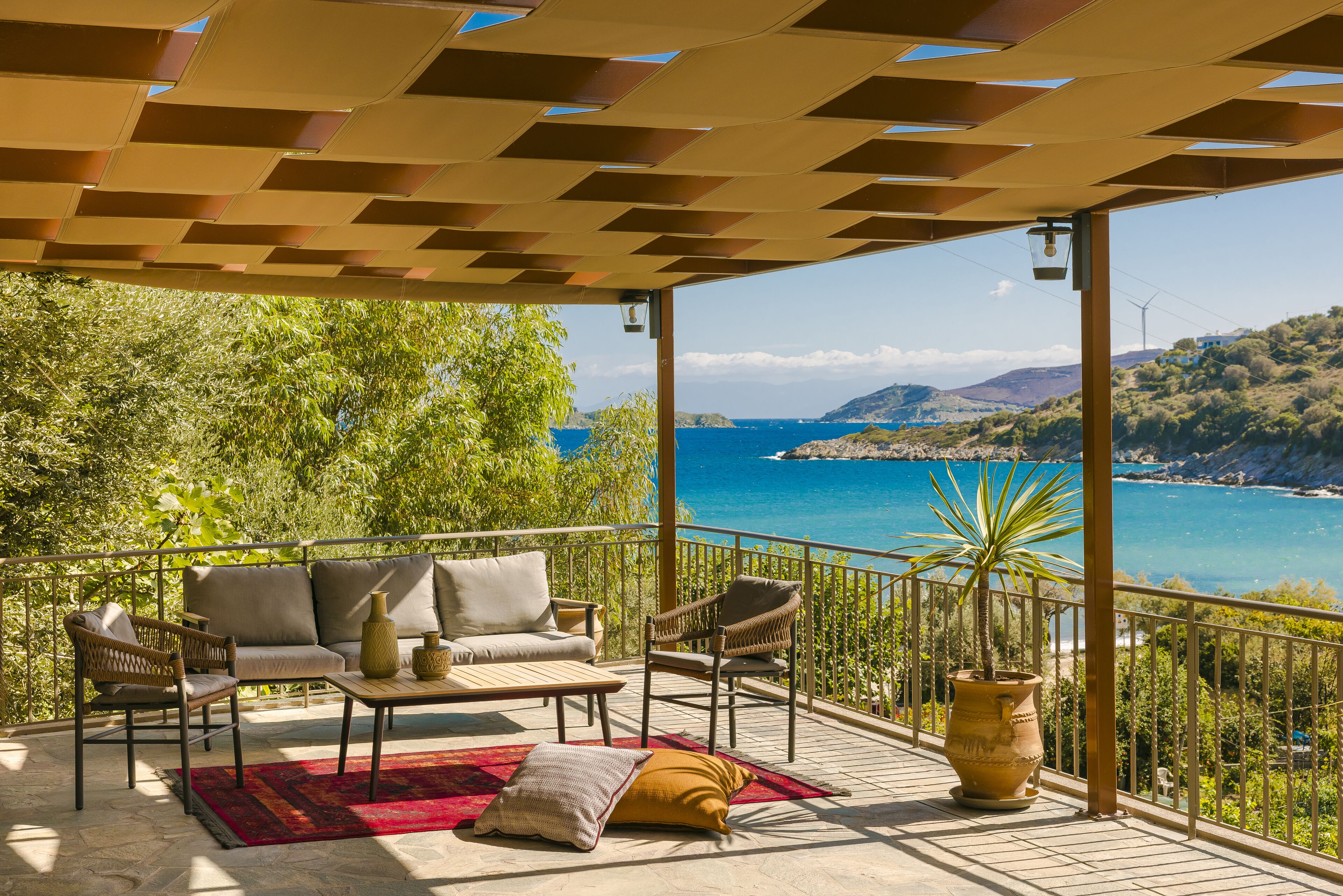 Un área de estar al aire libre techada con vista al mar y colinas.
