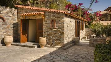 A stone building with a tiled roof, wooden doors, and large planters.