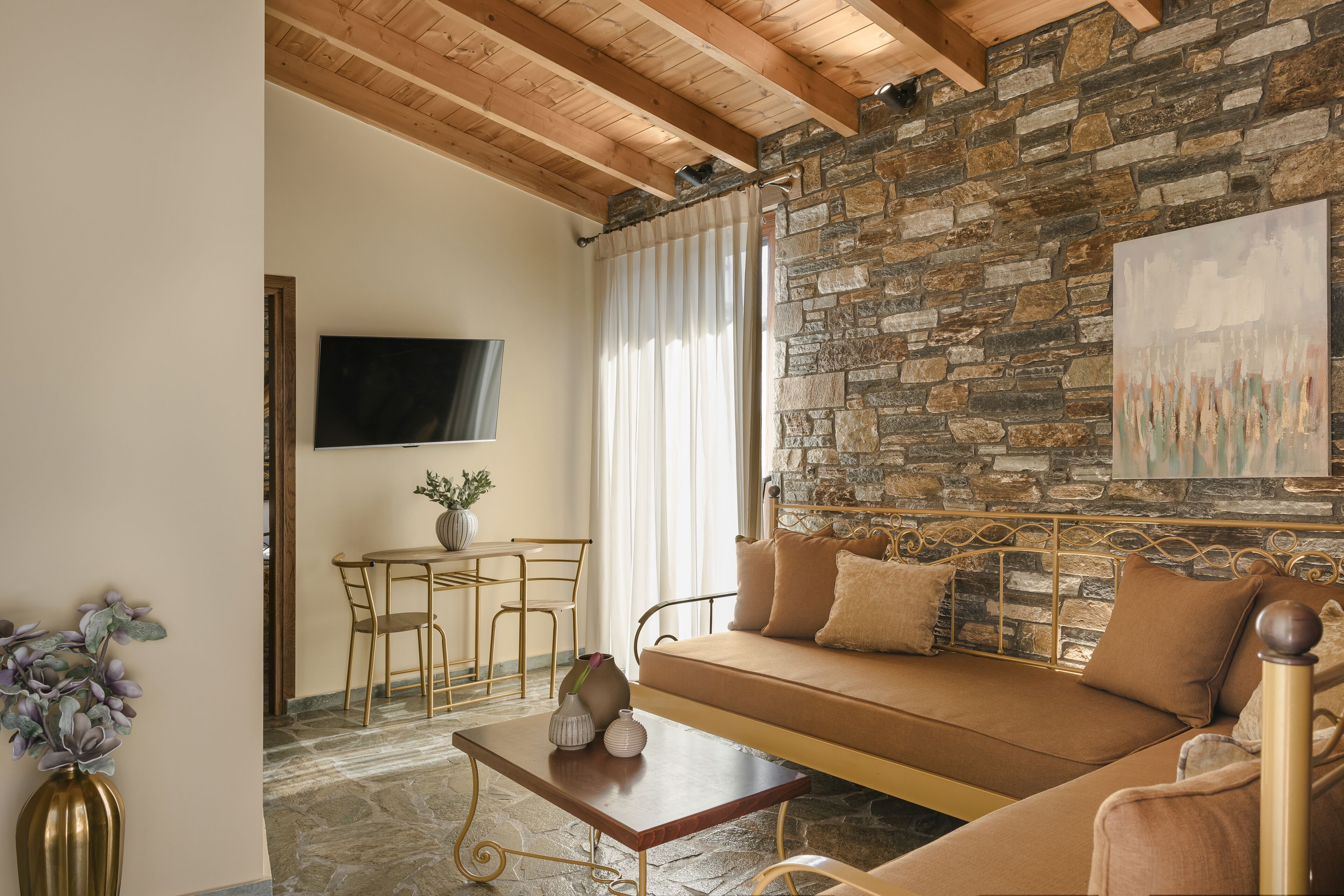 Una sala de estar acogedora con una pared de piedra, un sofá, una mesa de centro y un televisor montado en la pared.