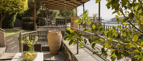 Un patio exterior con mesa, sillas, un jarrón grande y vistas al mar.