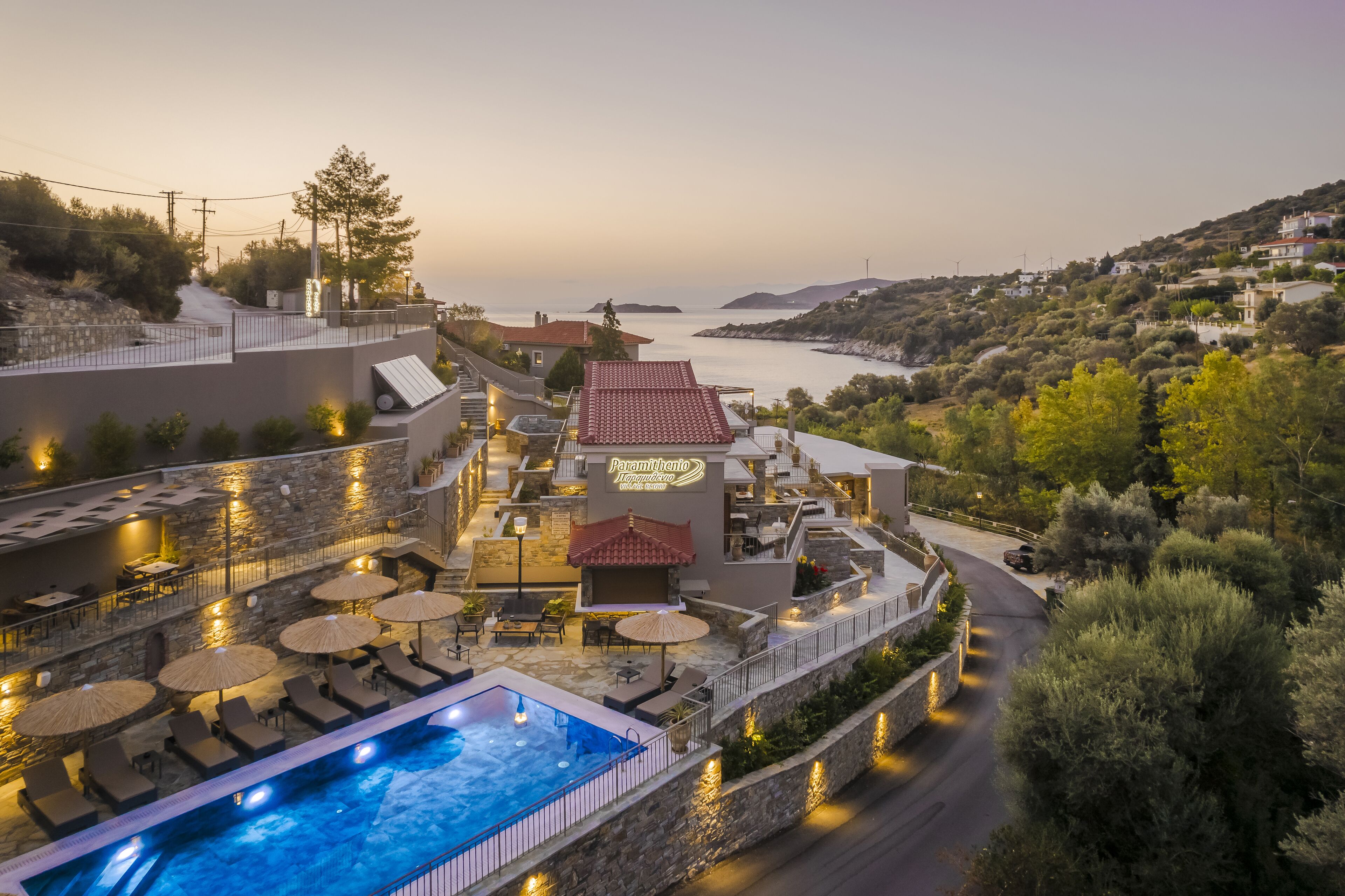 A hotel with a pool, outdoor seating, and a view of the sea.