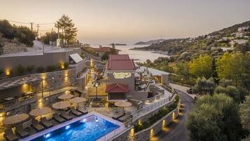 A hotel with a pool, outdoor seating, and a view of the sea.