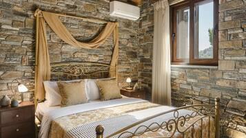 Un dormitorio con paredes de piedra, una cama, cortinas y una ventana.