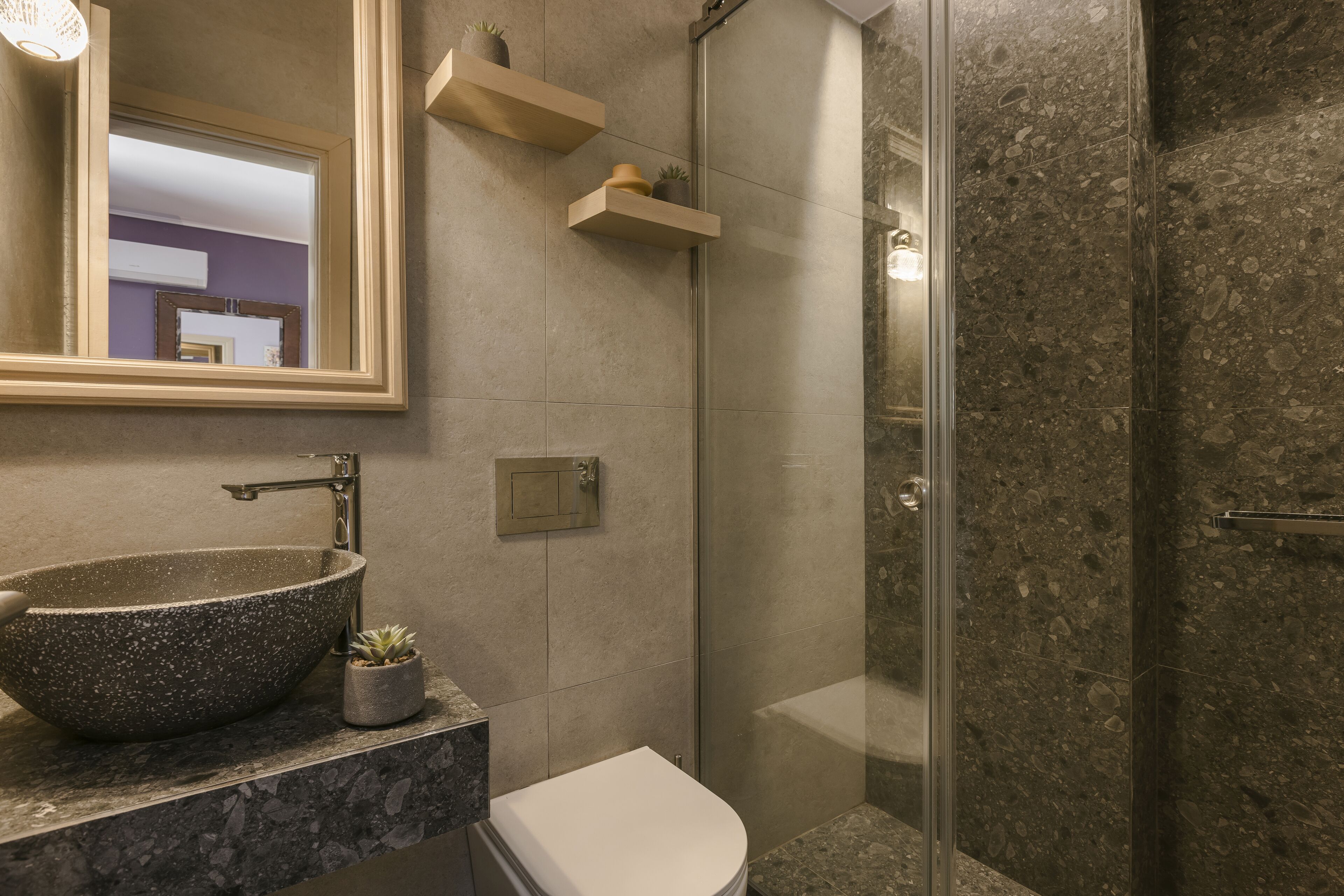 Een badkamer met een stenen wastafel, toilet en een douchecabine van glas.