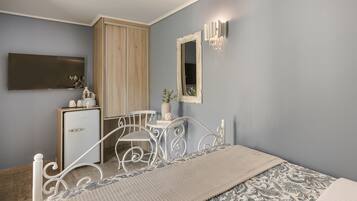 A bedroom with a bed, bedside table, dresser, mirror, and wall-mounted light fixture.