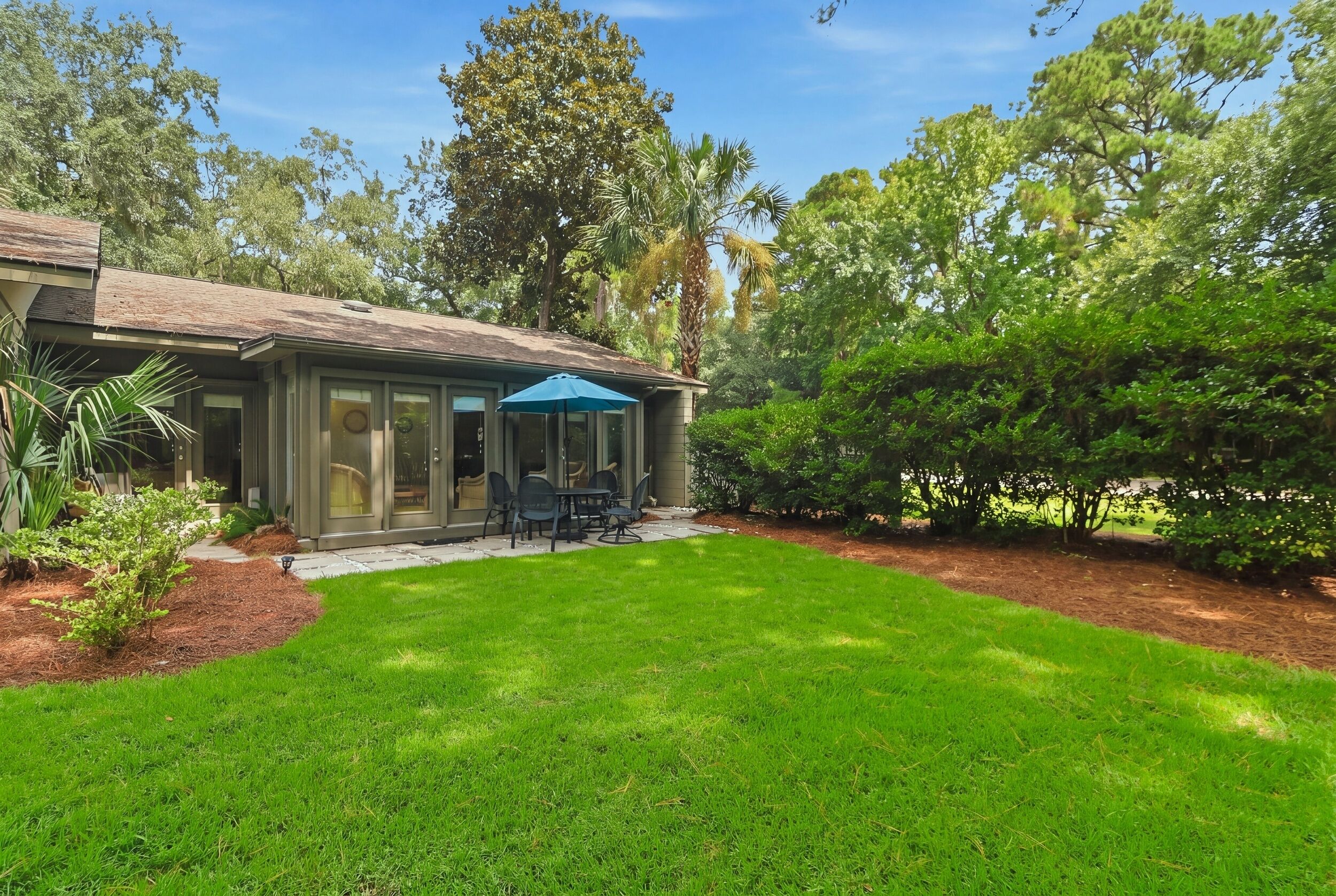 A residential property with a patio, outdoor seating, and a well-maintained lawn.