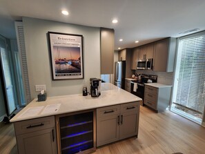 Una cocina moderna con una isla central, electrodomésticos de acero inoxidable y un cartel grande en la pared.