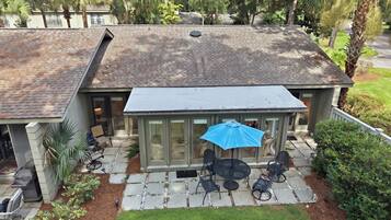 A house with a covered patio, outdoor seating, and a lawn.