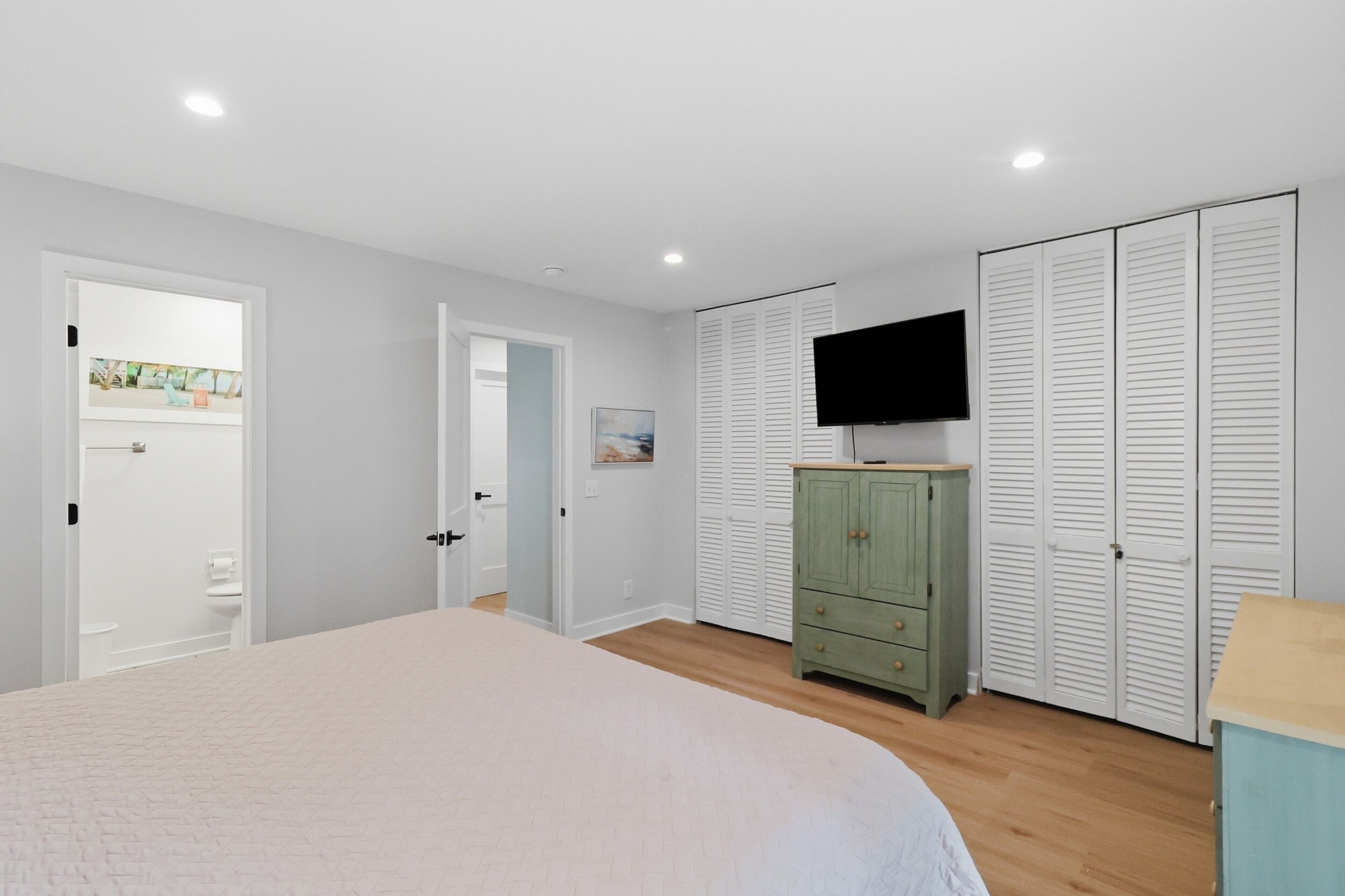 A bedroom with a bed, a wardrobe, a television, and a door leading to another room.