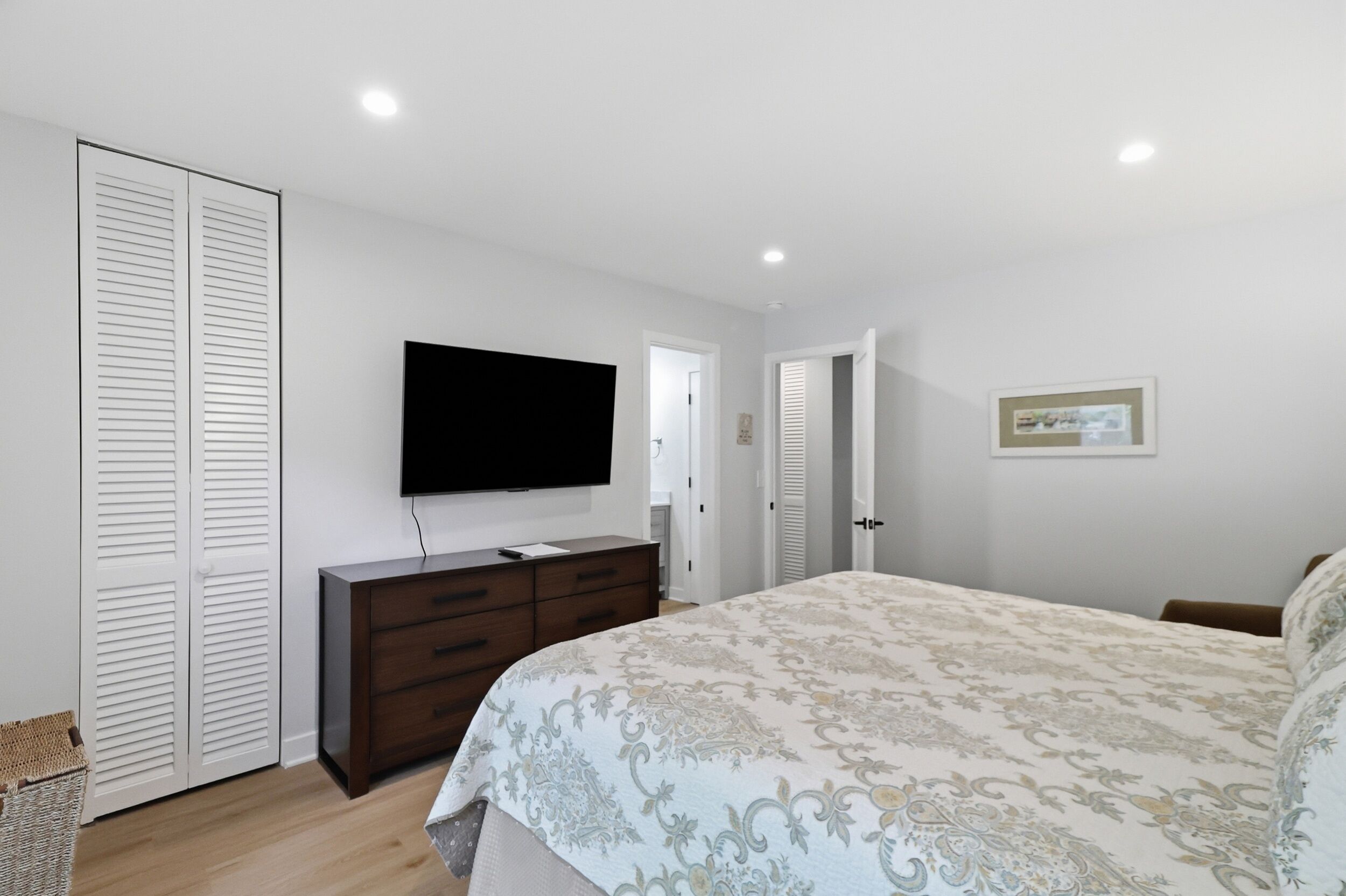 A bedroom with a bed, a dresser, a television, and a door.